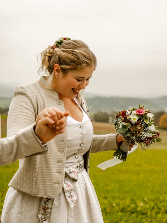 Braut im Trachtenkleid mit Brautstrauß auf einer Wiese